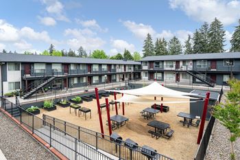 A courtyard with tables and chairs surrounded by a fence and apartment buildings.